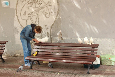 Young man feeding pigeons. Moscowのeditorial素材