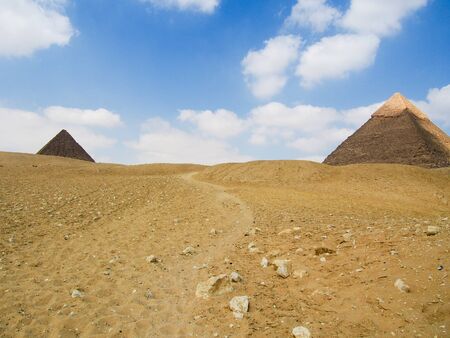 A path leads through the desert between two great pyramids in Giza Egypt.
