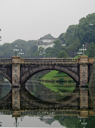 A traditional stone bridge reflects in the still water in front of the Japanese Imperial Palace in downtown Tokyo.のeditorial素材