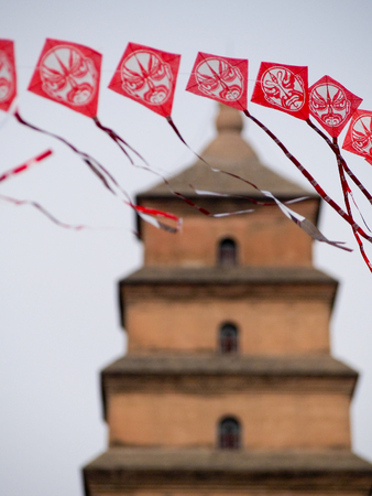 String of red Chinese kites with pagoda in the background.のeditorial素材
