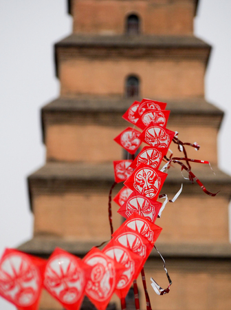 String of red Chinese kites with pagoda in the background.のeditorial素材