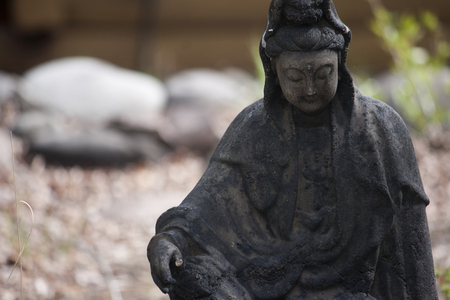 Small stone statue of Buddha in garden.のeditorial素材