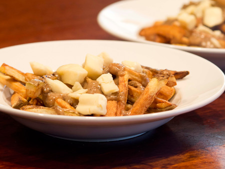 A bowl of homemade poutine, a Canadian dish made with fries, brown gravy, and cheese curds.