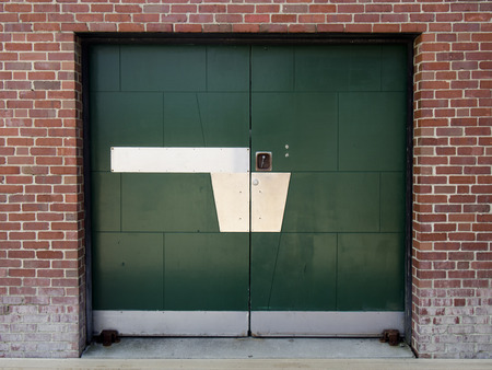 A green painted metal door in an old brick building.のeditorial素材