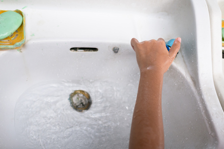 The girl washed her hands with green soap on the left side and was turning off the water.の写真素材