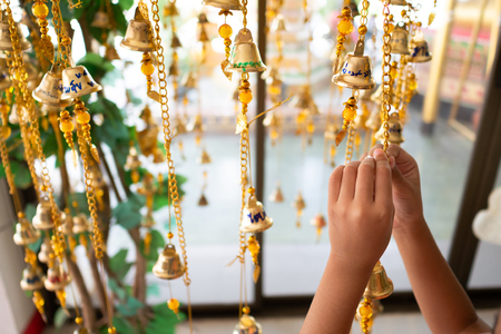 The hands of the girls are tied to the gold bells of the Buddhist faith. Thai beliefs, if written on the letter bells, will be lucky. Thai Temple, Select focus shallow depth of fieldの写真素材