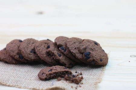 Chocolate chip cookies with a bite mark placed on a sack on a wooden table