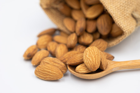 Almond seeds in wooden spoons. Group almonds on the woven sack. Select focus shallow depth of fieldの写真素材