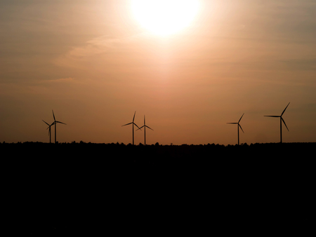 silhouette wind turbine in grass field with twilight in eveing