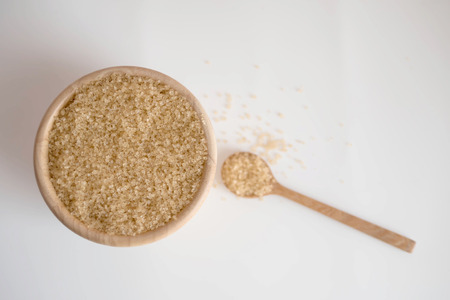 Brown sugar in a wooden bowl and wood spoon on white background with copy space and blurredの写真素材
