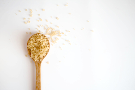Brown sugar in a wooden spoon on white background with copy space.の写真素材