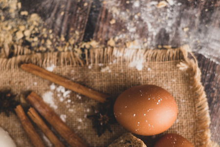 Cinnamon and eggs are placed on the sack and the flour is dropped on the wooden table.