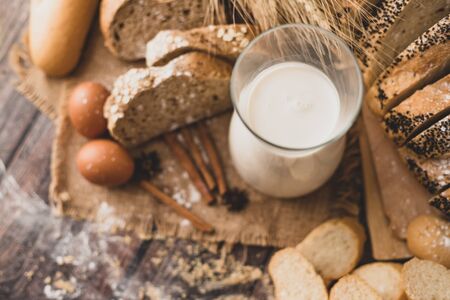 Milk in a glass bottle placed on a wooden table with ingredients for making bread and bakeryの写真素材