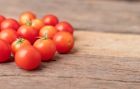 Group red tomatoes on the wooden table. Cherry tomato is a small that has a sweet, firm texture and has a pleasant aroma. And contains beta-carotene, vitamin C and high vitamin E.の写真素材