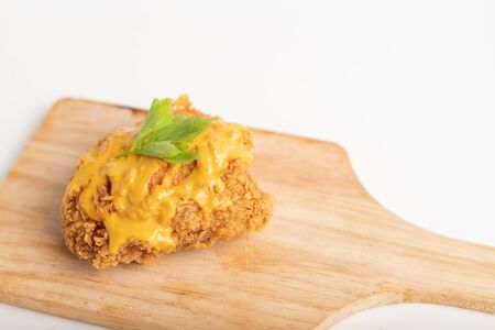 Chicken fried topped cheese on the wooden cutting board with white background.の写真素材