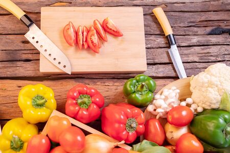 Top view tomato slice on the cutting board. Various vegetables placed on a wooden table which many fiber and health benefits.の写真素材