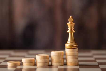 gold king on the step chip on board and wooden background. The winner concept.の写真素材