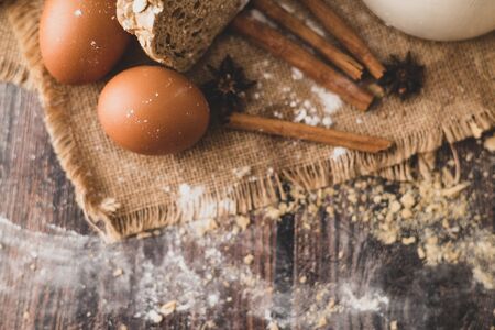 Cinnamon and eggs are placed on the sack and the flour is dropped on the wooden table.
