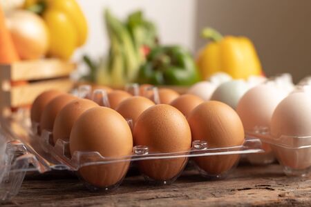Close up eggs of chicken and duck in plastic box placed on a wooden table with various vegetables. Select focus shallow depth of field and blurred background.の写真素材