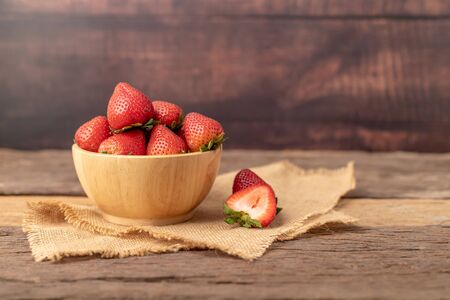 Strawberries are in a wooden bowl on a brown sack placed on the table.の写真素材