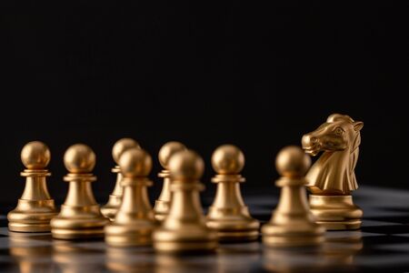gold horse stood in front of the pawn on the chess boardの写真素材
