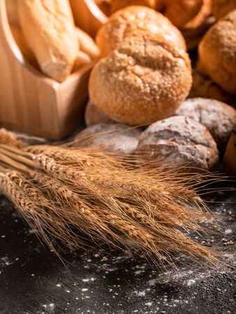 Close-up wheat and group bread on the black wooden table with sunlight in the morning. Selective focus.の写真素材