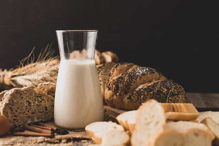 Milk in a glass bottle placed on a wooden table with ingredients for making bread and bakeryの写真素材