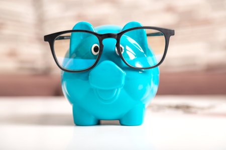 Close-up a blue piggy bank wearing black glasses on the wooden table. The symbol of saving money and wealth financial.の写真素材