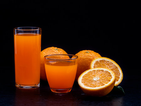 2 glasses of orange juice on the table. Freshness oranges fruit on the black background. Fresh healthy food.の写真素材