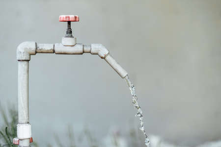 Water tap on the wall background. Old open metal-plastic crane. Ecology, water conservation, water shortage or drought concept. High quality photoの写真素材