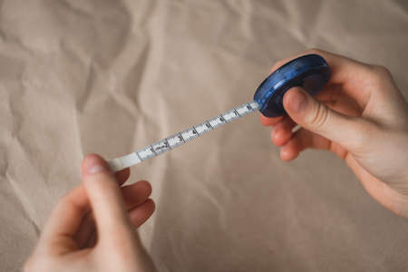 Woman holds centimeter measuring tape in hands on craft paper background. High quality photoの写真素材