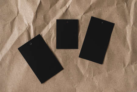 Black blank paper price tags isolated on craft paper, flat lay. High quality photo