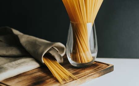 Wheat spaghetti pasta in glass on a wooden board. Healthy food background. High quality photo
