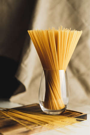 Wheat spaghetti pasta in glass on a wooden board. Healthy food background. High quality photoの写真素材