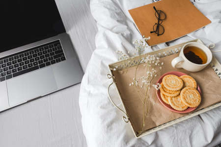 Breakfast in bed. White bed, a tray with tea and cookies. Morning at home. High quality photoの写真素材