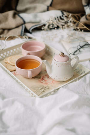 Kettle with tea and cups on a tray. Breakfast at home in bed, comfort and coziness. High quality...