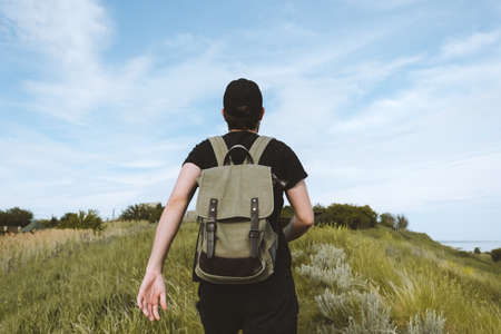 A young man tourist with a backpack climbs a mountain. Outdoor activities. High quality photoの写真素材