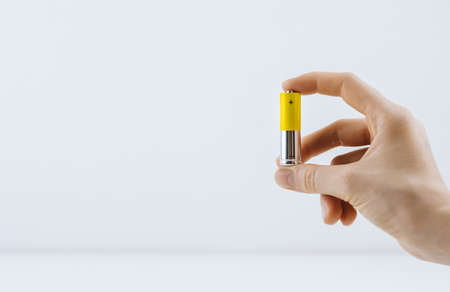 Female hand holds a salt battery isolated on white background, copy space.