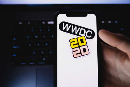 Hands holding smartphone with WWDC 2020 logo on the screen.