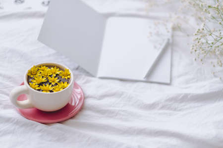 Cup with yellow flowers on a white bed. Spring background.の写真素材