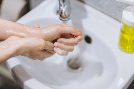 Woman washes hands on a white background. Concept of protection against germs.の写真素材