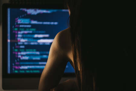 Young female programmer writes program code on a computer. Home officeの写真素材