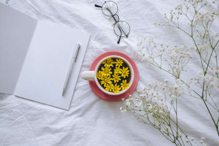Cup with yellow flowers on a white bed. Spring background.