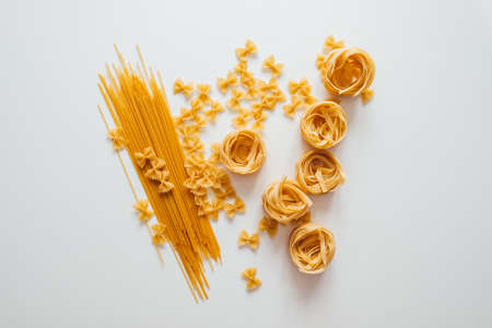 Varieties of Italian pasta. Spaghetti, farfalle and tagliatelle isolated on a white background, top view. Non-perishable food.の写真素材