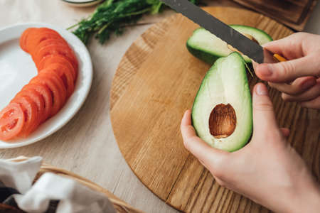 Cooking health sandwich with avocado and tomato at home in the kitchen. Proper nutrition.