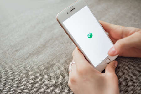 Russian bank Sberbank, hands holding iPhone with screen of Sberbank Online app.