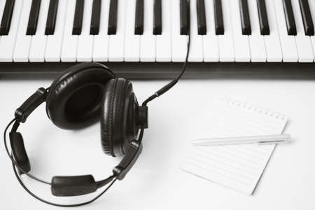 music template with keyboard synthesizer instrument with headphone on white background. Top view. Copy space. High quality photoの写真素材