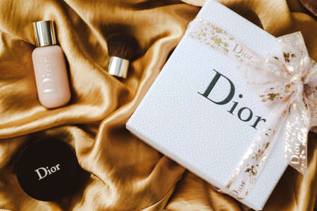 Gift box from DIOR with makeup on a golden fabric. High quality photoのeditorial素材