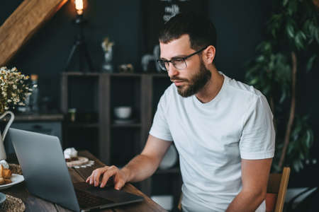 Young caucasian bearded man work at home, freelance work, use laptop computer. High quality photoの写真素材