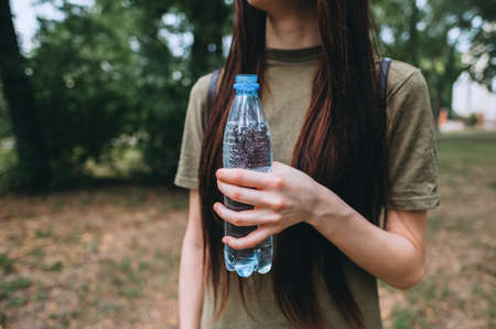 Young caucasian woman holding a blue plastic water bottle outdoor. High quality photo